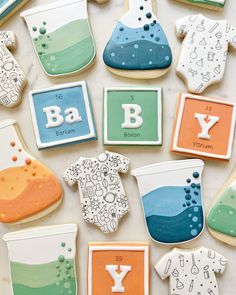 some cookies that are decorated with different types of baby clothes and letters on them, sitting on a table