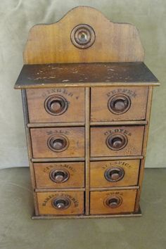 an old wooden cabinet with many drawers and knobs on the front, sitting against a wall