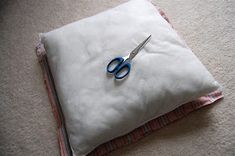 a pair of scissors sitting on top of a white pillow