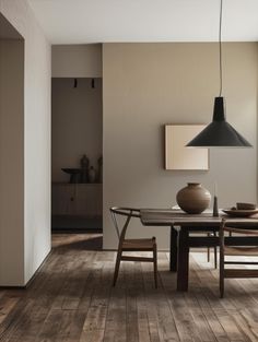 a dining room table with chairs and a vase on the table in front of it