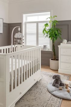 a white crib with a stuffed animal on the floor