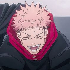 a man with pink hair wearing a black and red hoodie smiles at the camera