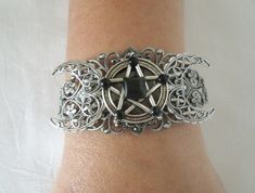 This beautiful silver plated filigree cuff bracelet has a silver plated triple moon design and a pewter silver pentacle with obsidian settings. Adjustable. Gothic Round Metal Jewelry, Adjustable Gothic Metal Bracelets, Mystical Jewelry Bracelet Gift, Mystical Silver Jewelry For Festival, Silver Gothic Jewelry For Jewelry Making, Gothic Silver Jewelry For Festival, Gothic Silver Festival Jewelry, Adjustable Silver Gothic Jewelry, Adjustable Gothic Silver Jewelry