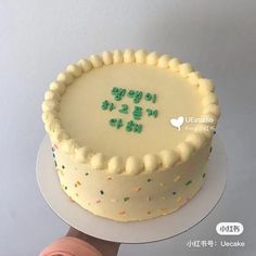 a hand holding a cake with the words happy birthday written on it