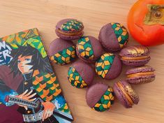 some macaroons are next to a book and an orange on a wooden table