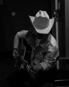 a man with a cowboy hat playing an acoustic guitar