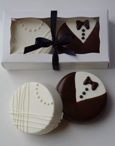 two chocolate covered pastries in a box with a bow tie on them and one is decorated like a groom's suit