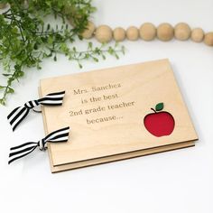 a wooden book with an apple on it and a ribbon around the cover that says, mrs sandeez is the best 2nd grade teacher because