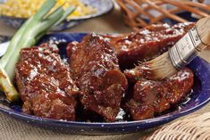 a blue plate topped with meat covered in marinara sauce and green onions next to a basket of corn