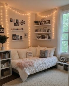 a living room filled with white furniture and lots of lights on the wall above it