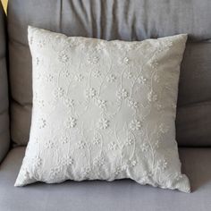 a white pillow sitting on top of a gray couch