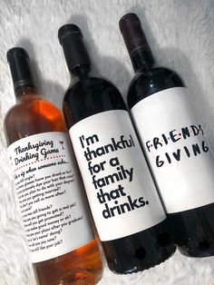 three bottles of wine sitting next to each other on a white blanket with writing on them