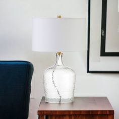 a table with a lamp on it and a blue chair in front of the wall