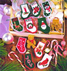 an assortment of knitted christmas stockings and candy canes in a box on a table