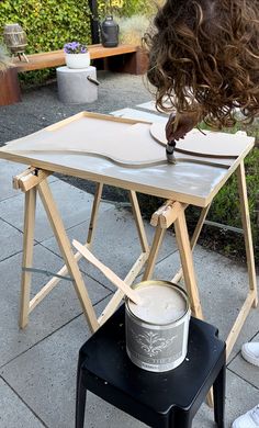 a woman is painting on a table outside