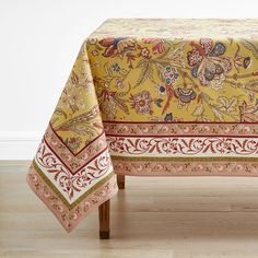 a yellow tablecloth with red and blue designs on it sitting on a wooden bench