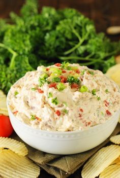 a white bowl filled with dip surrounded by chips