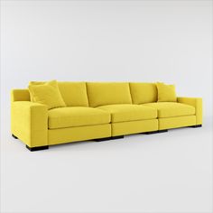 a large yellow couch with pillows on it's back and arms, sitting in front of a white wall