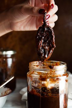 a person is dipping some food into a jar