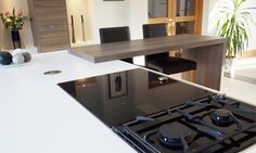 a black stove top sitting inside of a kitchen next to a table with chairs on it