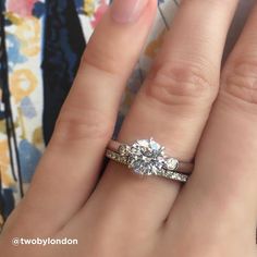 a close up of a person's hand with a diamond ring on their finger