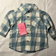 This New With Tags, Button Down Shirt Size 3-6 Months Is Adorable With A Blue And White Checkered Pattern, Buttons At The Elbows To Roll Up The Sleeves, And A Pleated Back. Ruggedbutts Is An Excellent Quality Clothing. Cute Blue Button-up Shirt, Blue Long Sleeve Shirt For Playtime, Blue Cotton Top For First Birthday, Cute Blue Collared Shirt, Cotton Button-up Tops For Playtime, Cotton Tops With Button Closure For Playtime, Blue Tops With Buttons For Playtime, Cute Fitted Blue Shirt, Blue Shirt With Buttons For Playtime