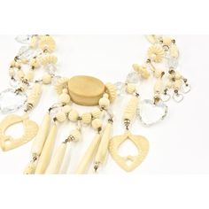 From a Miami socialite's estate, this necklace and matching earrings  are truly a statement piece.  Made in the 1980's, the necklace has carved and smooth bone pieces with gold tone bead accents as well as facetted crystal beads and hearts.    The necklace has sterling silver lobster clasp.  The earrings are 2.78" by .56" wide.  They have post backs so you must have pierced ears.  The necklace is 15" long and 7.25" wide at the bib area and .62" depth. Elegant Handmade Bone-colored Jewelry, Unique Carved Bone Jewelry, Vintage Handmade Cream Jewelry, Unique Bone-colored Carved Jewelry, Carved Bone, Bone Carving, Dangling Earrings, Bib Necklace, Bohemian Chic