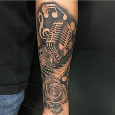 a man with a microphone and music notes on his arm is wearing a rose tattoo