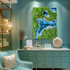 a painting is displayed on the wall above a blue chair in a room with green walls