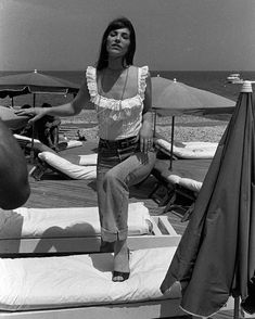 a woman sitting on top of a bed next to the ocean