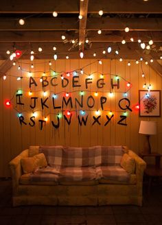 a couch sitting in front of a wooden wall covered in christmas lights and letters on it