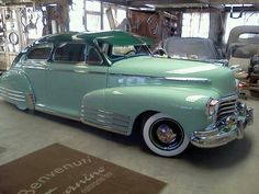 an old green car parked in a garage