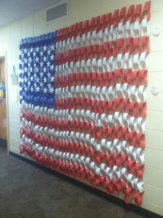 an american flag made out of red, white and blue ribbon is hanging on the wall