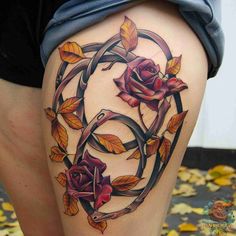 a woman's thigh with roses and leaves on the bottom part of her leg