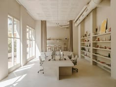 an office with two desks and chairs in front of large open windows on the wall