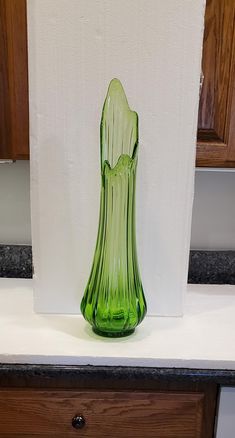 a green glass vase sitting on top of a counter next to a white paper towel