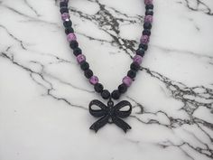 Bow Necklace - Black Bow Necklace - Pink and Black Necklace - Gothic Necklace - Pink and Black Necklace For Women - Bow Necklace For Women This necklace measures 17 1/2" in length.  This necklace is comprised of a black metal black jeweled bow pendant, pink acrylic beads with black swirls of color on them, and black acrylic multifaceted beads.  This necklace is strung on beading wire with a lobster clasp for closure.  So I found the black bow pendant and I fell in love with it.  The black jewels on it give it a great sparkle.  So to compliment the bow I used pink and black beads.  This necklace has a Gothic look.  This necklace is great for concerts and music events! Gift Black Ribbon Choker Necklace, Black Necklace With Ribbon For Gift, Gothic Black Necklaces With Round Beads, Black Gothic Necklaces With Round Beads, Gothic Black Necklace For Gift, Adjustable Black Necklace With Black Ribbon, Black Ribbon Jewelry For Gift, Purple Necklace With Black Beads For Gift, Black Pendant Choker As A Gift