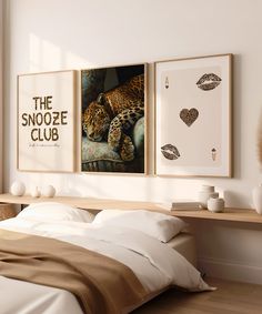 two framed pictures hang above a bed in a room with white walls and wood flooring