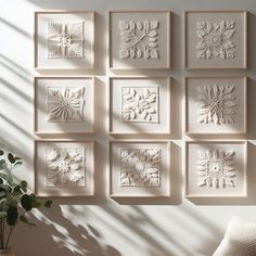 nine white wall art pieces hanging on the wall next to a plant in a vase