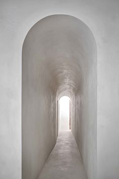 an empty white tunnel with light at the end