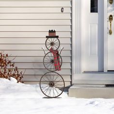 an old fashioned bicycle is standing in front of a house with snow on the ground