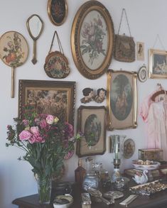 there are many framed pictures on the wall with flowers in vases next to them