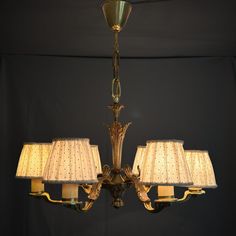 a chandelier with five lamps hanging from it's sides and four shades off