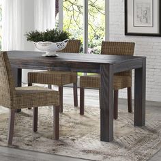 a dining room table with chairs and a rug in front of the window that overlooks an outdoor patio