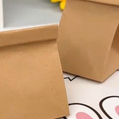 a brown paper bag sitting on top of a table next to a yellow flower vase