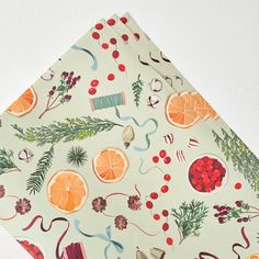 an orange and cranberry christmas wrapping paper on a white background with red berries, pine cones, evergreens, holly branches, mist, and other holiday decorations