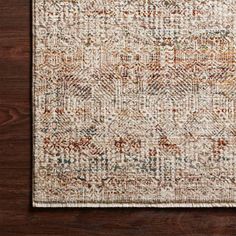 an area rug with brown and white colors on top of a wooden floor next to a wall