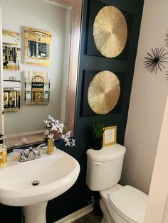 a white toilet sitting next to a sink in a bathroom under two gold circles on the wall