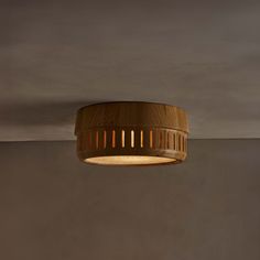 a wooden light fixture hanging from the ceiling in a room with grey walls and flooring