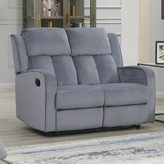 a grey reclining sofa sitting on top of a rug